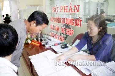 Cán bộ Văn phòng đăng ký quyền sử dụng đất thành phố Yên Bái hướng dẫn người dân làm thủ tục cấp Giấy chứng nhận quyền sử dụng đất. (Ảnh: L.C)

