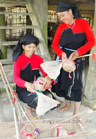 Chị Âu Thị Chính (người ngồi) chuẩn bị đạo cụ múa cho Đội văn nghệ thôn Đá Trắng.
