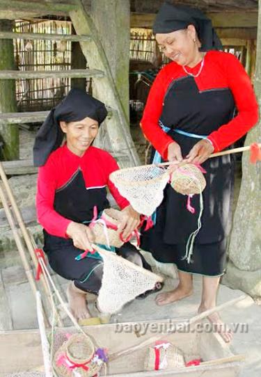 Chị Âu Thị Chính (người ngồi) chuẩn bị đạo cụ múa cho Đội văn nghệ thôn Đá Trắng.
