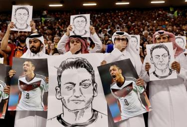 Cổ động viên Qatar giơ ảnh Ozil trên khán đài.