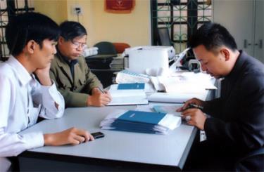 Cán bộ BHXH huyện Lục Yên kiểm tra sổ BHXH cho người lao động.
