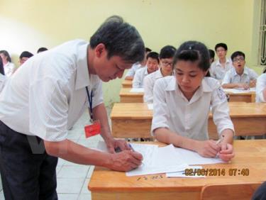 Giám thị ký vào giấy thi cho thí sinh trong kỳ thi tốt nghiệp trung học phổ thông năm 2014.