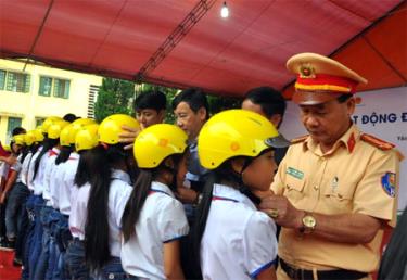 Lãnh đạo Ban ATGT tỉnh hướng dẫn học sinh đội mũ bảo hiểm đúng cách.
