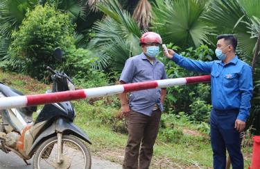 Bí thư Đoàn xã Xuân Lai - Phương Đức Dũng đo thân nhiệt cho người dân qua chốt kiểm soát dịch bệnh Covid-19.