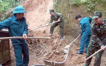 Ban Chỉ huy quân sự huyện Yên Bình cùng lực lượng dân quân xã hót đất sạt lở giúp gia đình bà Lương Thị Loan, thôn Hương Lý, xã Đại Đồng.