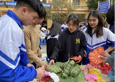 Các em học sinh say sưa với trải nghiệm gói bánh chưng trong dịp Tết cổ truyền dân tộc.