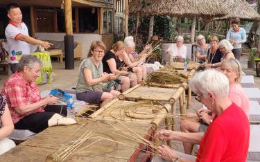 Foreign tourists experiencing shrimp basket weaving in Vu Linh Commune, Yen Binh District.