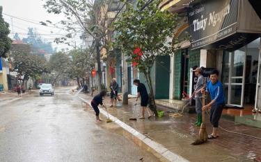 Nhân dân tổ 6, phường Minh Tân, thành phố Yên Bái tranh thủ dọn dẹp khi xe rửa đường công nghiệp đi qua.  (Ảnh: Thủy Thanh)