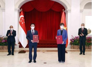 Vietnamese President Nguyen Xuan Phuc (first, left) and Singaporean Prime Minister Lee Hsien Loong (first, right) witness the exchange of cooperation documents between the two countries on February 25.