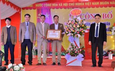 Lãnh đạo huyện Trấn Yên tặng hoa chúc mừng và trao Bằng công nhận đạt chuẩn nông thôn mới kiểu mẫu cho thôn Đức Quân. (Ảnh: T.L)