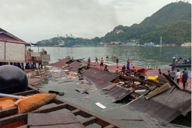 Mọi người đứng trên mái nhà bị sập xuống sông ở Jayapura, tỉnh Papua phía Đông Indonesia.