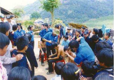 Thanh niên tình nguyện cắt tóc gội đầu cho trẻ em xã vùng cao Văn Chấn. (Ánh: Đặng Phương Lan)