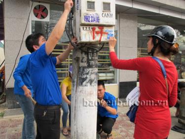 Đoàn viên thanh niên tham gia bóc dỡ biển quảng cáo và quét vôi cột điện ngay sau lễ ra quân Tháng thanh niên 2015.