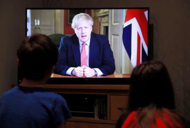 Hai đứa trẻ theo dõi Thủ tướng Anh Boris Johnson phát biểu qua truyền hình ngày 23-3.