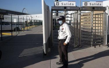 Một nhân viên bảo vệ đứng tại cửa khẩu El Chaparral, thành phố biên giới ở Tijuana, Mexico.