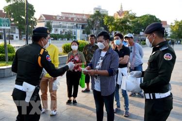 Cảnh sát phát khẩu trang cho người dân để phòng dịch COVID-19 tại Phnom Penh, Campuchia.