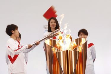 Vận động viên bóng đá Nhật Bản Azusa Iwashimizu (trái) thắp sáng ngọn đuốc Olympic tại lễ rước đuốc Olympic Tokyo 2020, ở Naraha, tỉnh Fukushima, Nhật Bản, ngày 25/3/2021.