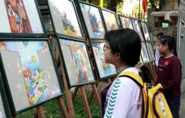 Các thí sinh nhỏ tuổi thưởng lãm tranh vẽ đẹp trước khi bước vào Cuộc thi vẽ tranh Áo dài. Ảnh: THÚY BÌNH