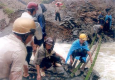 Ông Hờ Bùa Tu - Chủ tịch xã Tà Xi Láng, huyện Trạm Tấu (ngồi giữa) đang chỉ đạo đội cứu hộ, cứu nạn tập kết vật liệu làm cầu tạm cho dân đi lại.
