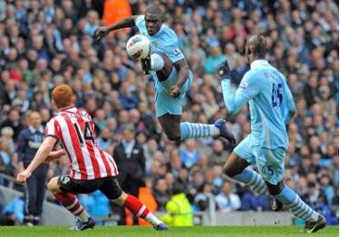 Hậu vệ Micah Richards (giữa) của Man.City chặn đường bóng đến tiền vệ Jack Colback của Sunderland (áo đỏ).