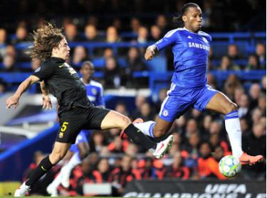 Tiền đạo Didier Drogba vượt qua hậu vệ Carles Puyol của Barcelona.