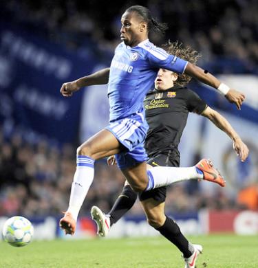 Tiền đạo Didier Drogba vượt qua trung vệ Puyol của Barcelona trong trận lượt đi.