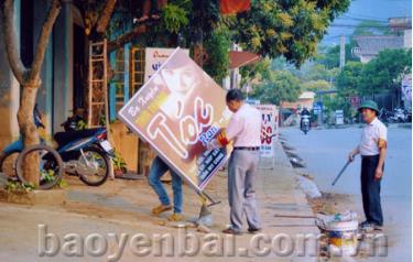 Các thành viên của đội tự quản thị trấn Nông trường Nghĩa Lộ nhắc nhở, tuyên truyền người dân không để biển quảng cáo lấn chiếm hành lang, vỉa hè.
