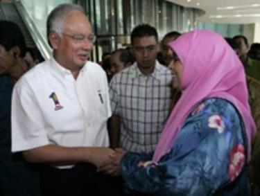 Thủ tướng Najib Razak (trái) trò chuyện với một người ủng hộ tại buổi lễ kỷ niệm 100 ngày cầm quyền.