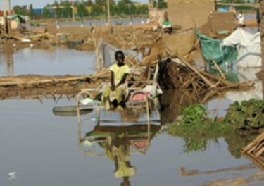 Một bé gái đang ngồi bên ngoài túp lều bị hư hại do lũ lụt ở Khartoum, Sudan.