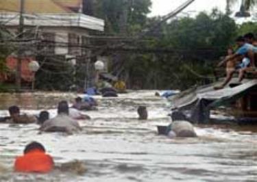 Người dân ở thành phố Pasig thuộc vùng ngoại ô thủ đô Manila lội trong nước lũ để sơ tán trong ngày 27/9. Một số người vẫn ngồi trên nóc nhà.