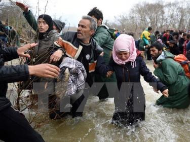 Người di cư và tị nạn cố gắng vượt sông qua khu vực biên giới Hy Lạp-Macedonia để tới Macedonia ngày 14/3/2016.