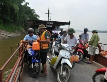 Thành viên Tổ tự quản an toàn giao thông tại bến đò Y Can  phát dụng cụ nổi cầm tay cho khách đi đò.