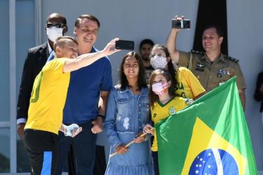 Tổng thống Jail Bolsonaro và con gái Laura (giữa) không đeo khẩu trang khi chụp ảnh cùng những người ủng hộ bên ngoài dinh tổng thống hôm 3/5.