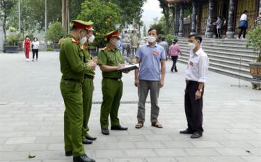 Thượng úy Nông Minh Tràng (giữa) hướng dẫn các biện pháp đảm bảo an ninh trật tự cho tổ tự quản về ANTT tại đền Đông Cuông