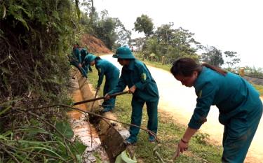 Các chiến sĩ dân quân huyện Trạm Tấu giúp dân khơi thông cống rãnh, vệ sinh môi trường tại các tuyến đường.