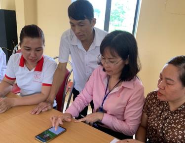 Cán bộ NHCSXH Chi nhánh tỉnh Yên Bái tuyên truyền, hướng dẫn người dân sử dụng ứng dụng VBSP Smart Banking tại điểm giao dịch xã.