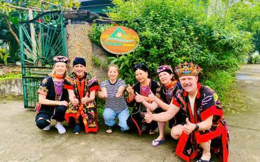 Foreign visitors are delighted to try on traditional ethnic costumes during their cultural experience in Vu Linh Commune, Yen Binh District.