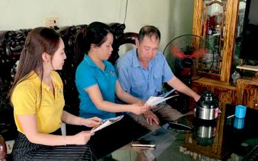 Viên chức BHXH khu vực XVII phối hợp với cán bộ bưu điện tuyên truyền chính sách BHXH tự đóng, BHYT tại hộ gia đình.