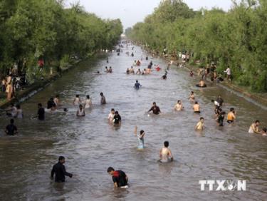 Người dân tự làm mát trên dòng kênh trong bối cảnh nắng nóng ở thành phố Lahore, miền đông Pakistan.