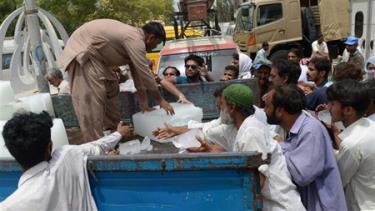 Người dân Pakistan nhận nước đá bên ngoài một bệnh viện ở Karachi hôm 24-6.