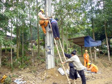 Cán bộ Điện lực Trấn Yên lắp công tơ điện cho đồng bào Mông xã Hồng Ca. 
