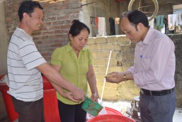 Cán bộ Trung tâm Khuyến nông tỉnh (bên phải) kiểm tra chất lượng cám ngô, cám gạo ủ chế phẩm EMINA của gia đình bà Nguyễn Thị Bích.