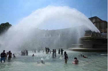 Người dân tránh nắng nóng bên vòi phun nước ở Paris, Pháp.