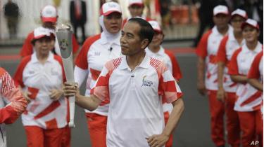 Tổng thống Indonesia Joko Widodo cầm ngọn đuốc Asian Games trong một buổi lễ ở Merdeka Palace, Jakarta ngày 17/8/2018.