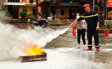 Cán bộ Phòng cháy chữa cháy và Cứu nạn, cứu hộ, Công an tỉnh Yên Bái hướng dẫn thầy, cô giáo cách sử dụng bình chữa cháy xách tay dập tắt khay xăng, dầu đang cháy.