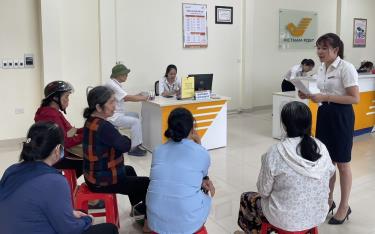 Cán bộ Bưu điện huyện Văn Chấn tuyên truyền, vận động người dân đăng ký nhận lương hưu qua tài khoản ATM.