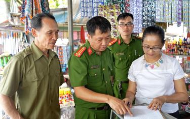 Ông Lê Văn Tích (bìa trái) phối hợp với lực lượng Công an phường tổ chức cho hộ kinh doanh tại chợ Nguyễn Phúc ký cam kết không vi phạm hành lang an toàn giao thông.