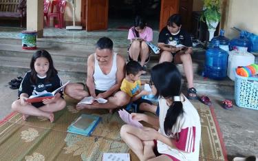 Ông Trần Văn Long - Trưởng dòng họ Trần thị trấn Trạm Tấu cùng các cháu đọc sách, chia sẻ tri thức.