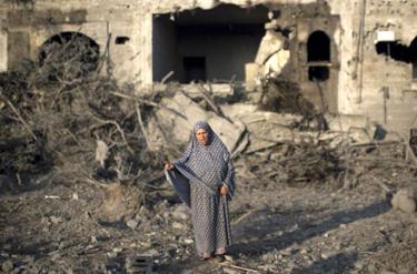 Một phụ nữ Palestine đứng trên đống đổ nát sau đợt không kích của phía Israel.
