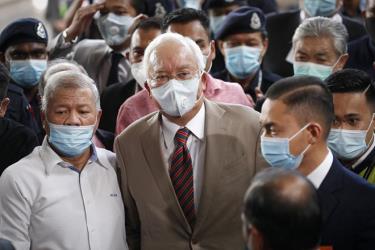 Ông Najib (giữa) đeo khẩu trang ra tòa hôm 28-7.